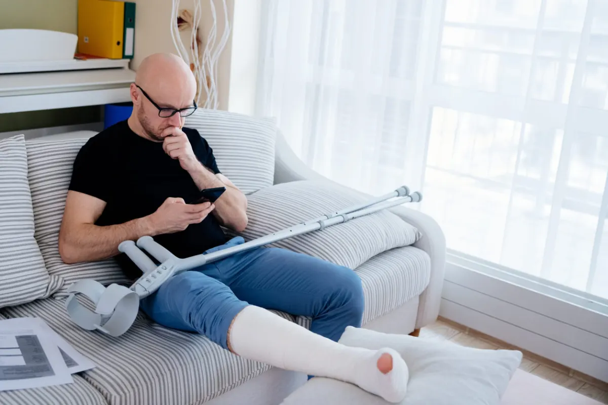 Injured man with a leg cast and crutches at home after an accident